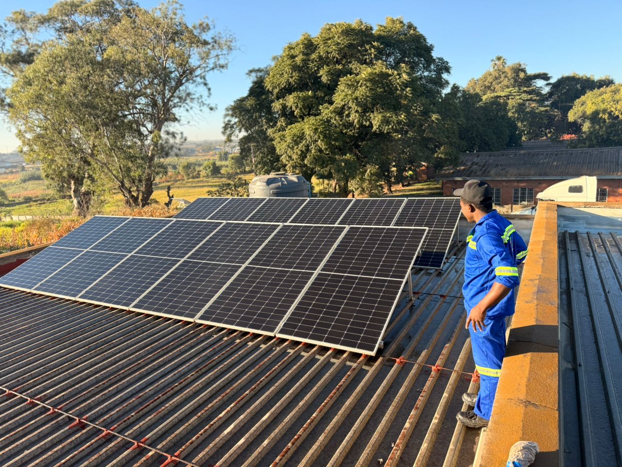 Amostron engineer in hi-vis vest installing solar panels on commercial roof