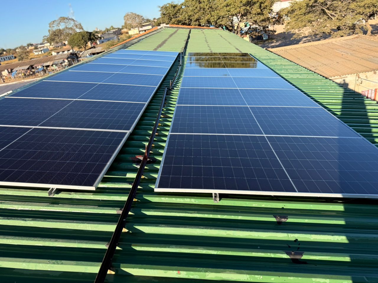Commercial rooftop solar on green sheet metal — large array